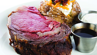 prime rib with loaded baked potato and sauces