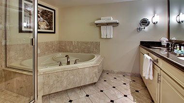 hotel bathroom with vanity, jacuzzi tub, and shower