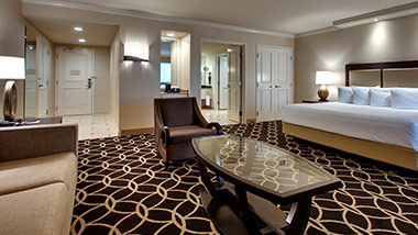 hotel suite with king bed, sitting chair, master bathroom