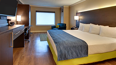 hotel room with king bed, tv, office desk, sitting chair
