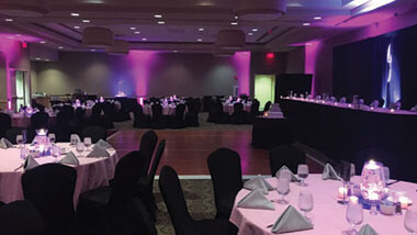 Circular tables with dark chairs surround a wooden dance floor inside the banquet space at Hollywood Casino in St. Louis, Missouri.