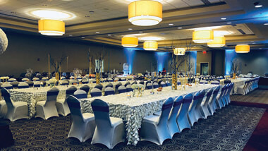 Long rectangle banquet tables with decorative table cloths and spandex chair covers.