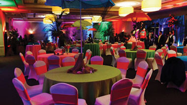 Chairs covered in bright material surround circular tables with green table cloths and palm tree center pieces at Hollywood Casino in St. Louis, Missouri.