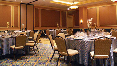 Wood-paneled banquet space filled with circular tables and chairs inside Hollywood Casino in St. Louis, Missouri.