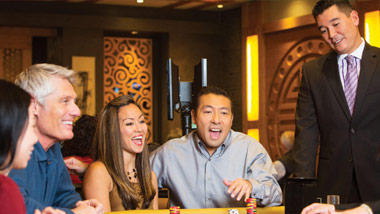 players and asian casino host at a gaming table