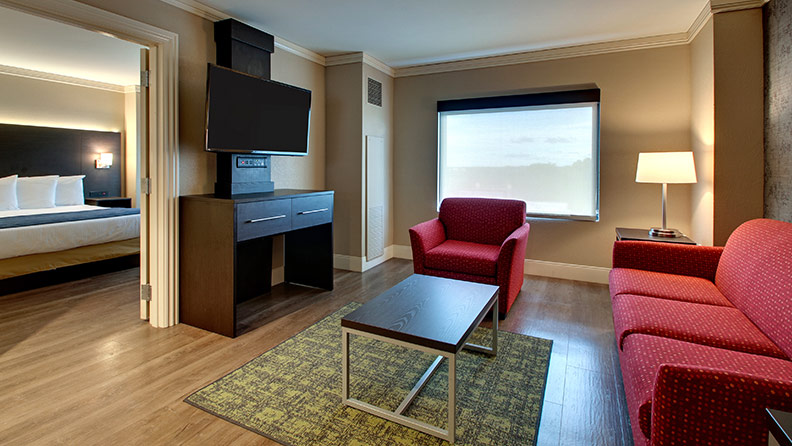 Hotel suite with tv, red couch, red sitting chair, coffee table