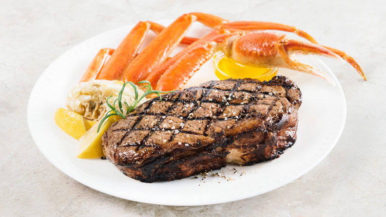 strip steak with crab legs and lemons